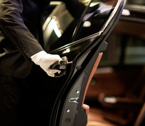 A chauffeur in white gloves opening the door of a luxurious limo