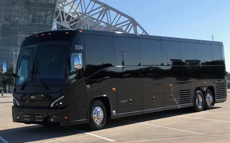 Black luxury charter bus parked outdoors near modern building