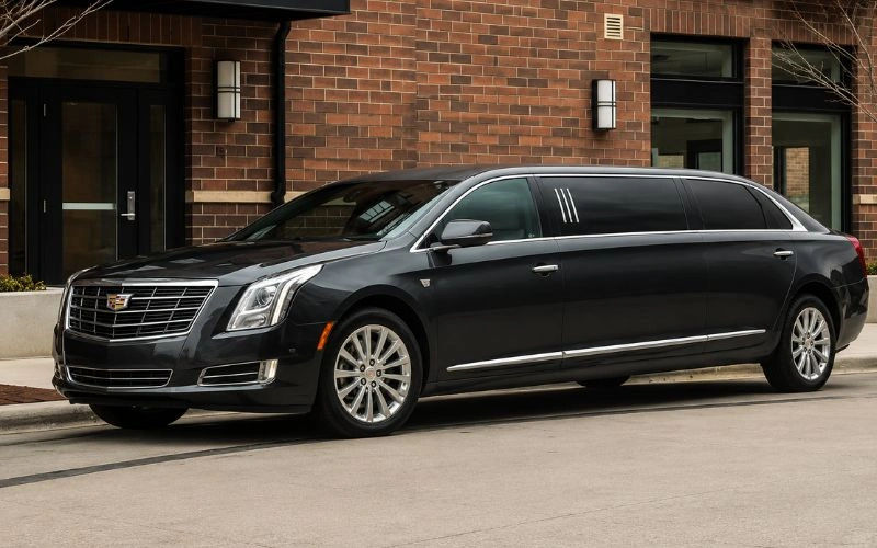 Black luxury limousine parked outside a brick building.