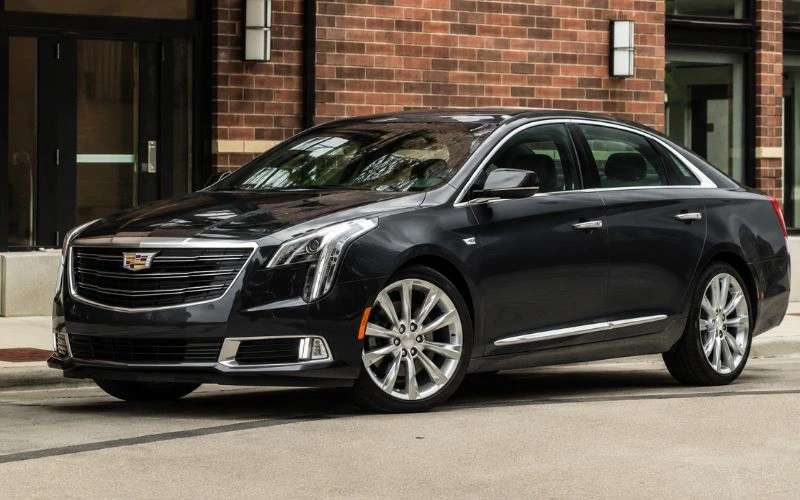 Black luxury sedan parked outside a brick building.