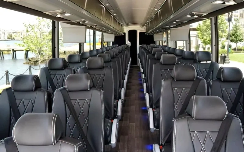 Luxury coach bus interior with black leather seats and spacious aisle view